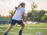 Niña jugando futbol en campo