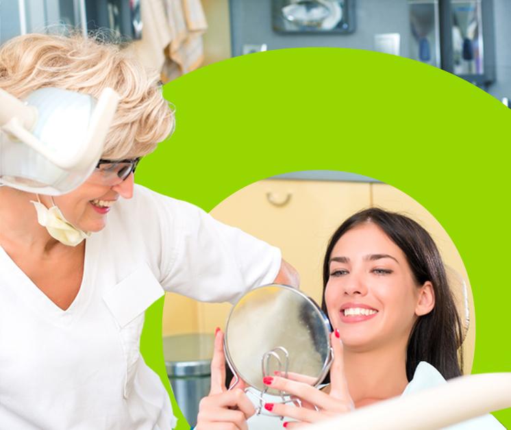 Mujer sonriente viendo su nueva sonrisa junto a su doctora Mujer sonriente viendo su nueva sonrisa junto a su doctora